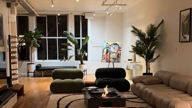 Una sala de estar moderna con chimenea, sofás y un ventanal grande.