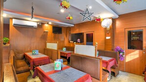 Un ristorante con cabine e tavoli, pareti in legno, decorazioni al soffitto e un condizionatore d'aria.