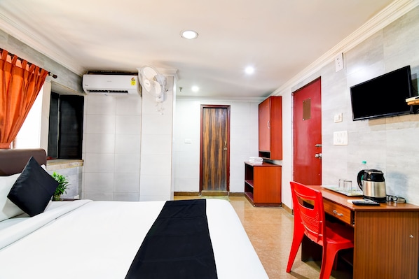 Una camera d'albergo con un letto, una scrivania, una sedia, una TV e angolo cottura.