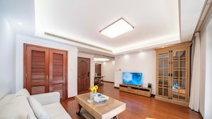 A living room with a sofa, coffee table, wooden cabinets, and a TV. - Tyms Gubei Apt 2BR Residence near Gubei (Shanghai)