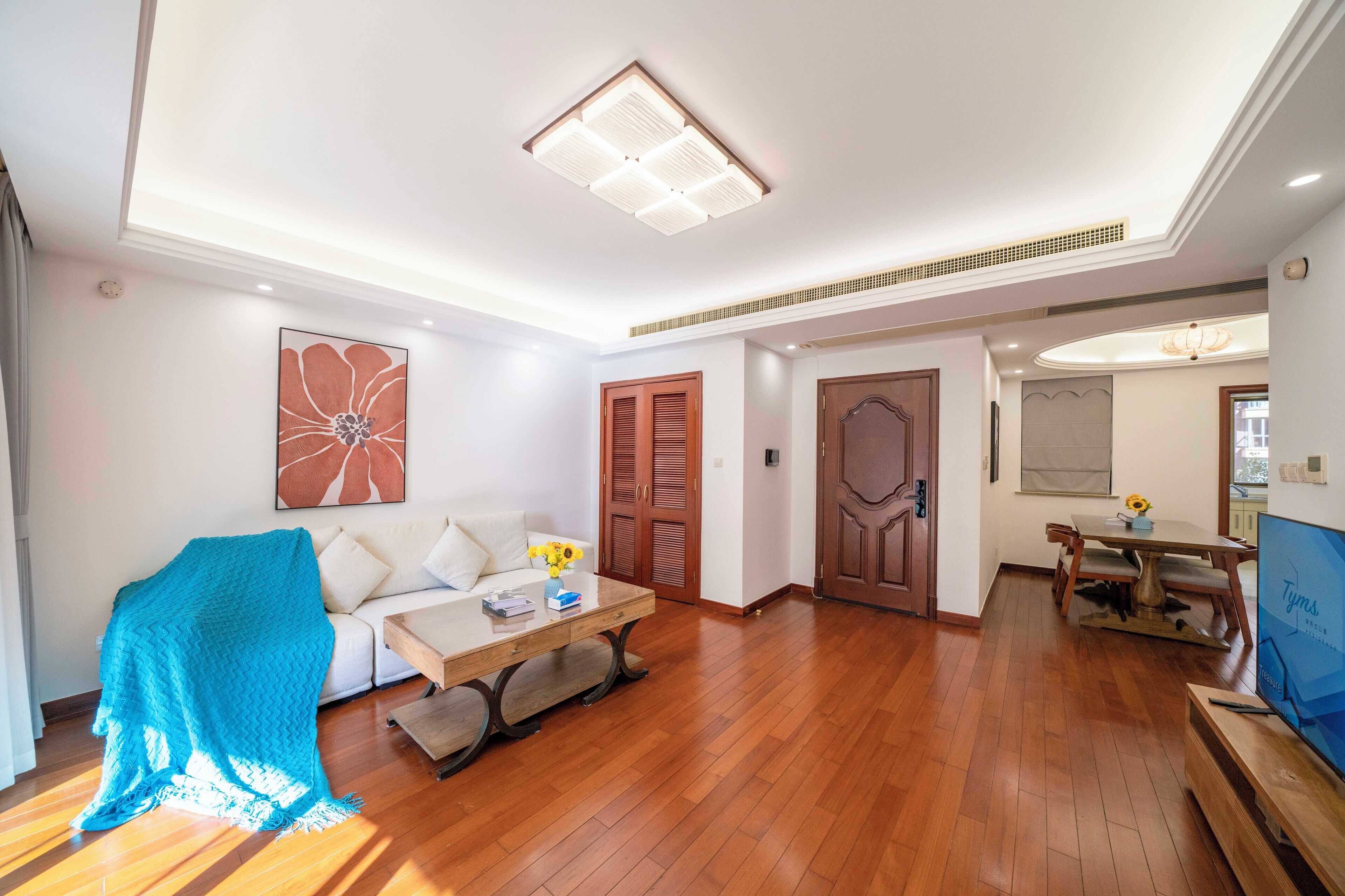 A modern living room with a wooden floor, a sofa, a coffee table, and a TV.