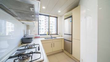 Een koelkast, een magnetron, een kookplaat, kookgerei, borden en bestek