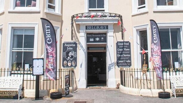 Un edificio en esquina con varias ventanas y un cartel que dice 'BELGRAVE Hotel, Restaurant & Bar'.