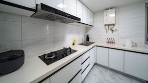 Une cuisine moderne avec des meubles blancs, une cuisinière noire, un four encastré et un évier en acier inoxydable.