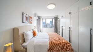 Une chambre d’hôtel avec un lit, une lampe de chevet, une fenêtre avec des rideaux et une armoire.
