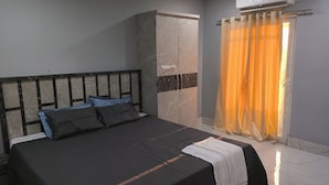 Un dormitorio con cama, armario y ventana con cortinas.