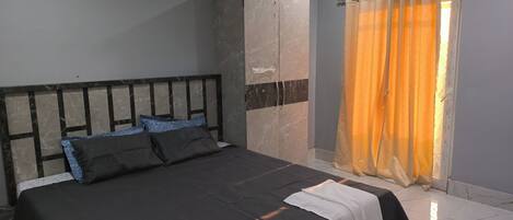 Un dormitorio con cama, armario y ventana con cortinas.