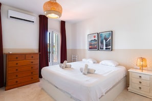 A hotel room with a bed, a dresser, a nightstand, and two wall-mounted artworks. - Summer Azul 3 Casa Lena by Casasol (Nerja)