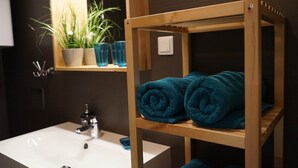 Un baño con un estante de madera que sostiene toallas, un lavabo y un espejo encima.