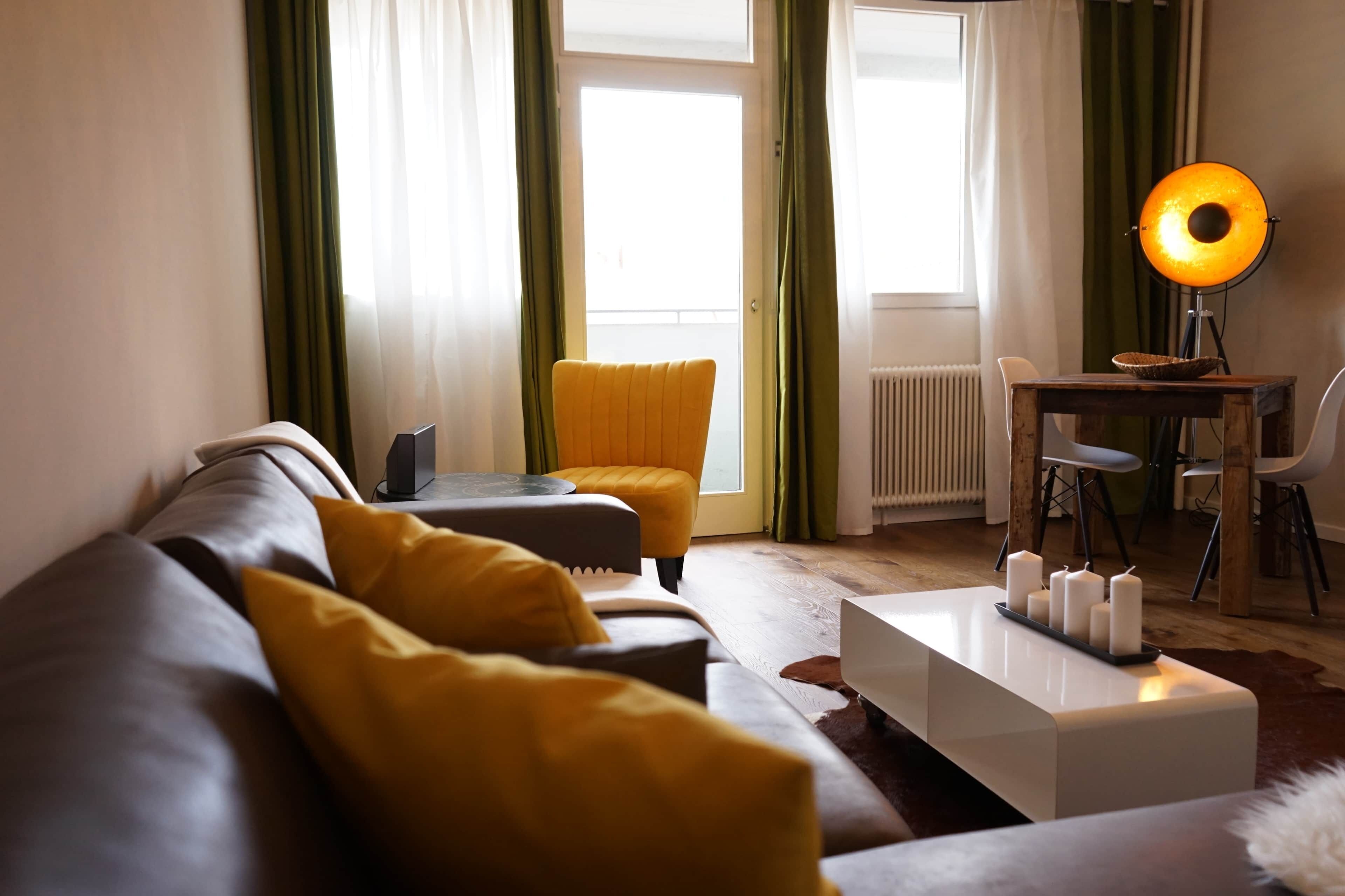 Un salon moderne avec un canapé, un pouf et une table basse agrémentée de bougies.