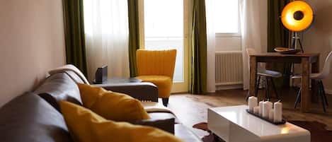 A modern living room with a sofa, ottoman, and a coffee table with candles.