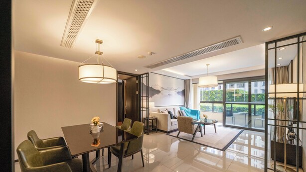 A modern hotel room with a dining area, a sofa set, and a large window offering a view of greenery. - Tyms Gubei Apt 2BR Apt Near Takashimaya (Shanghai)