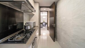 A modern kitchen with stainless steel appliances, a black stovetop, and a microwave. - Tyms Gubei Apt 2BR Apt Near Takashimaya (Shanghai)