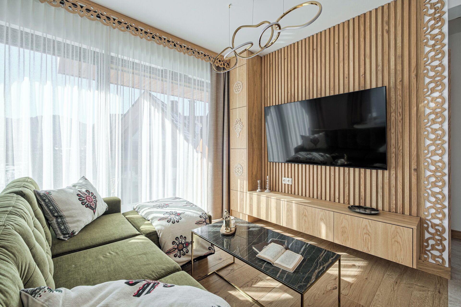 A living room with a sofa, a coffee table, and a TV mounted on a wooden wall.