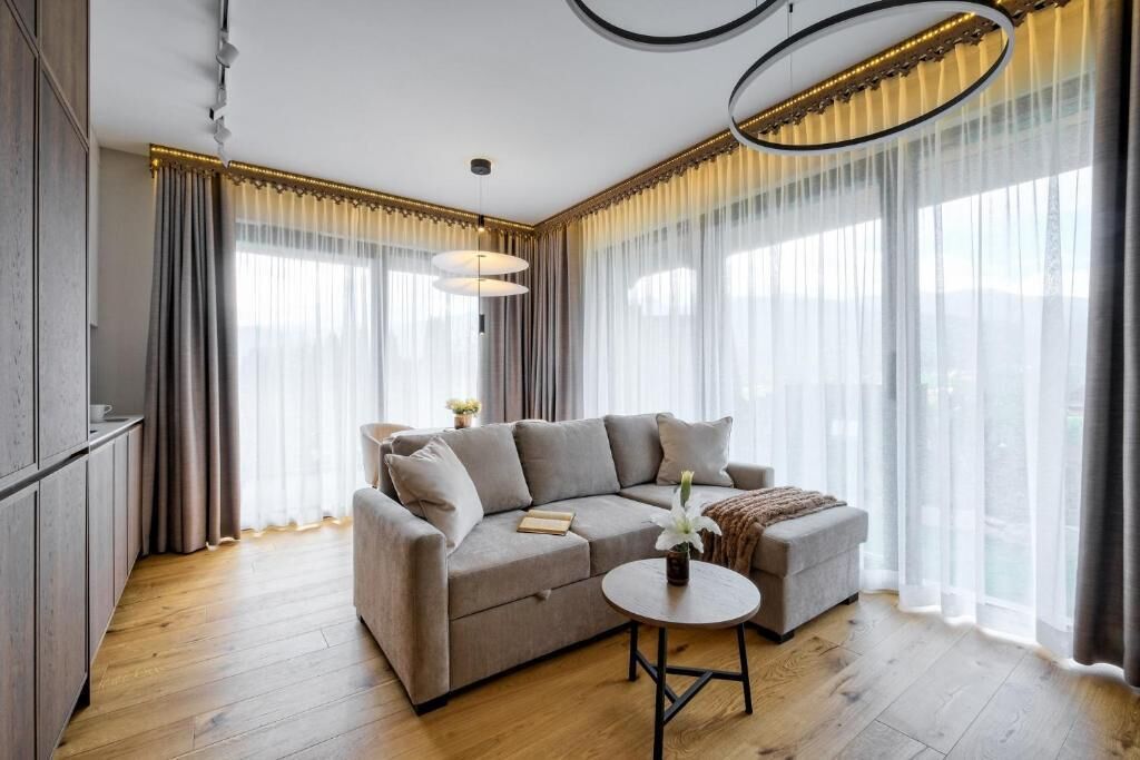 A modern living room with a grey sectional sofa, a round coffee table, and a pendant light.