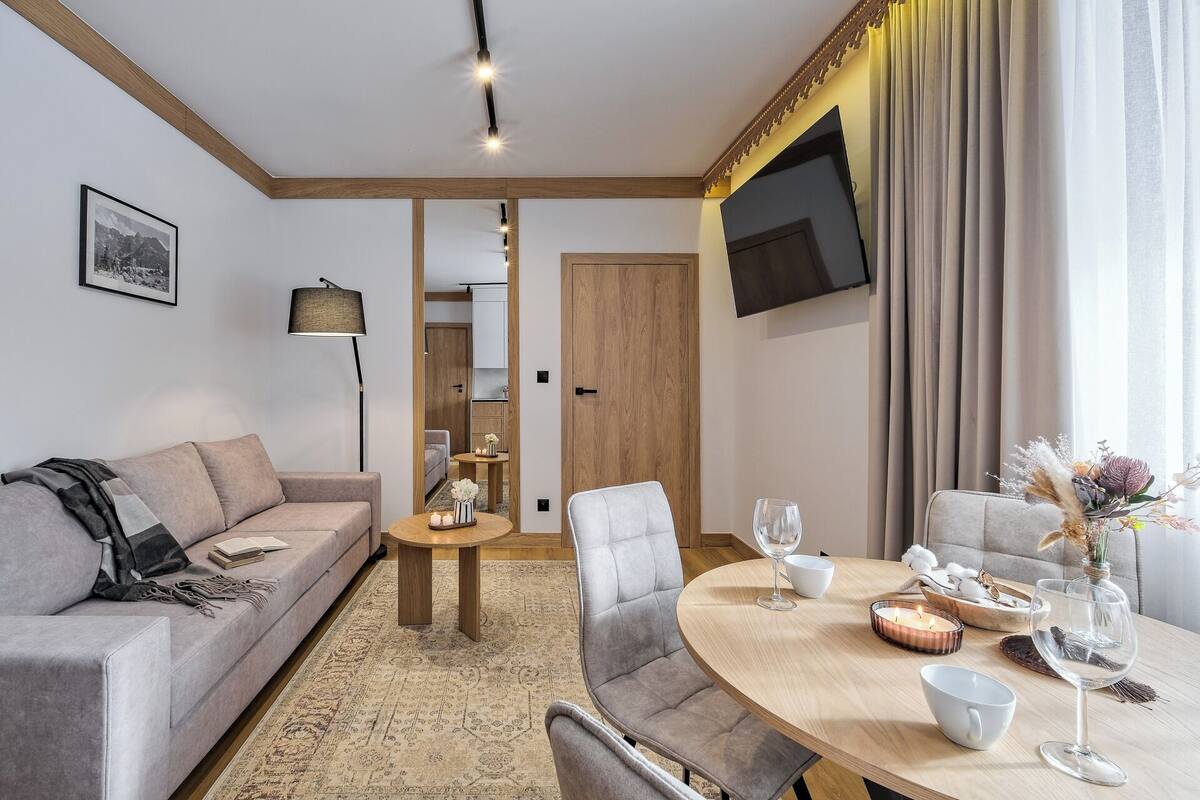 A modern living room with a sofa, a coffee table, and a dining table set for four.