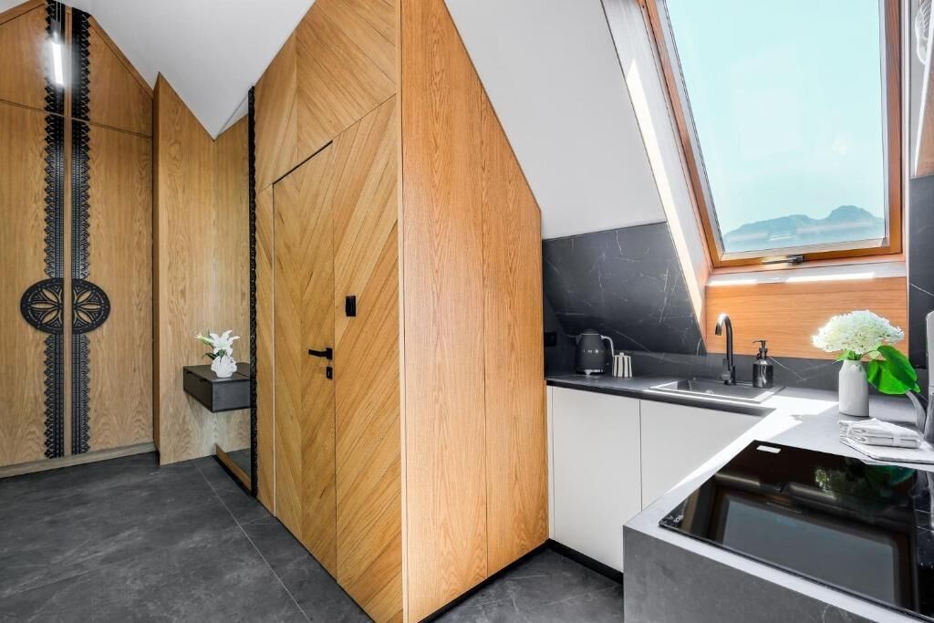 Een moderne keuken met houten kastjes, een zwart aanrecht en een raam met uitzicht op de bergen.