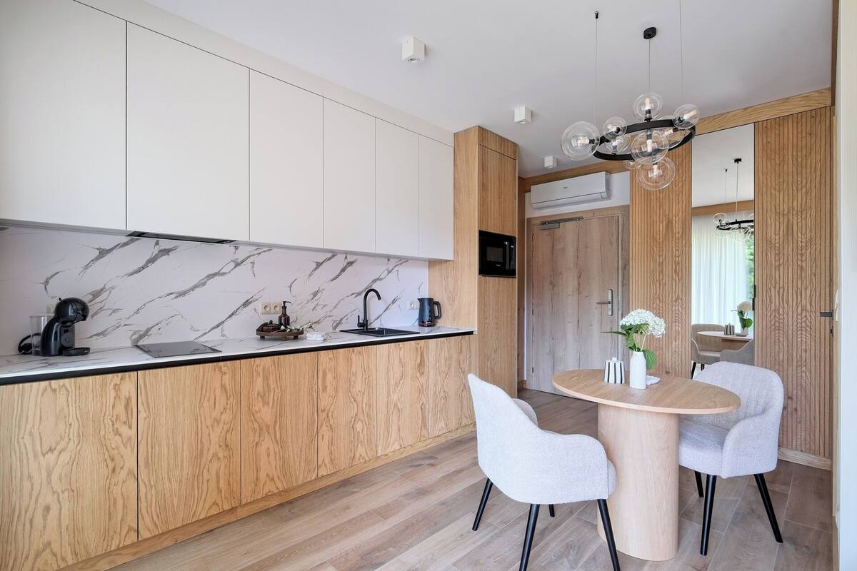 A modern kitchen with marble backsplash, wooden cabinets, and a round dining table with chairs.