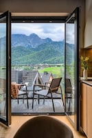 A balcony with a view of mountains and a wooden deck.