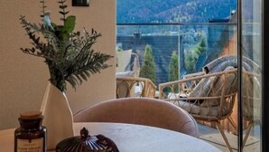Ein Balkon mit Bergblick, einem runden Tisch mit Stühlen und einer Pflanzvase.