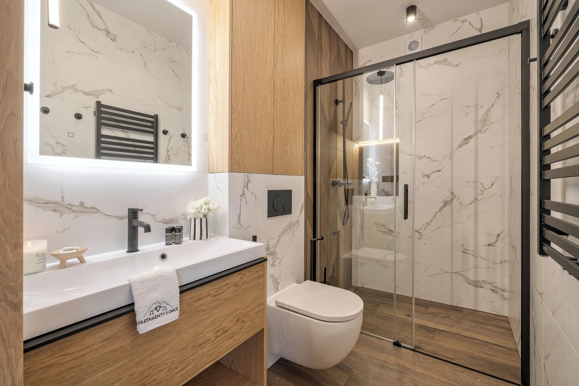 Et moderne badeværelse med en marmorvask, en glasbrusekabine og et toilet.