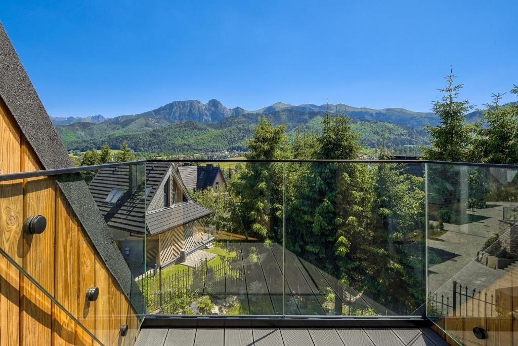 Un edificio moderno con balcón de vidrio que da a un paisaje montañoso.
