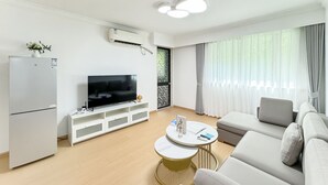 A modern living room with a flat-screen TV, white sofa, and a small round table. - Tyms Gubei 2BR Apt near Gubei Road (Shanghai)