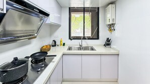 A modern kitchen with white cabinets, a stainless steel range hood, a window with a view, and a sink. - Tyms Gubei 2BR Apt near Gubei Road (Shanghai)