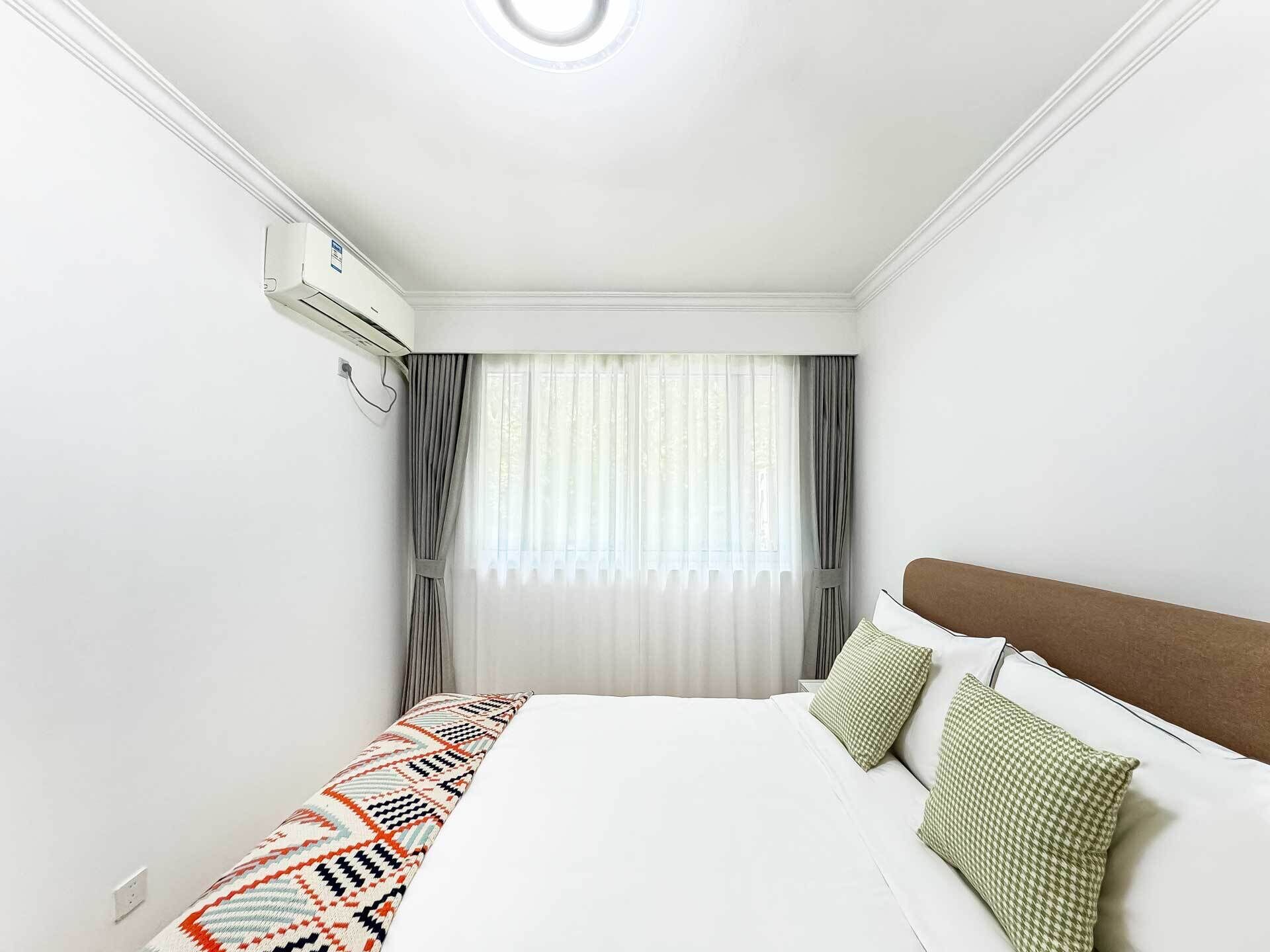 Une chambre d’hôtel avec un lit, une fenêtre avec des rideaux et un appareil de climatisation.