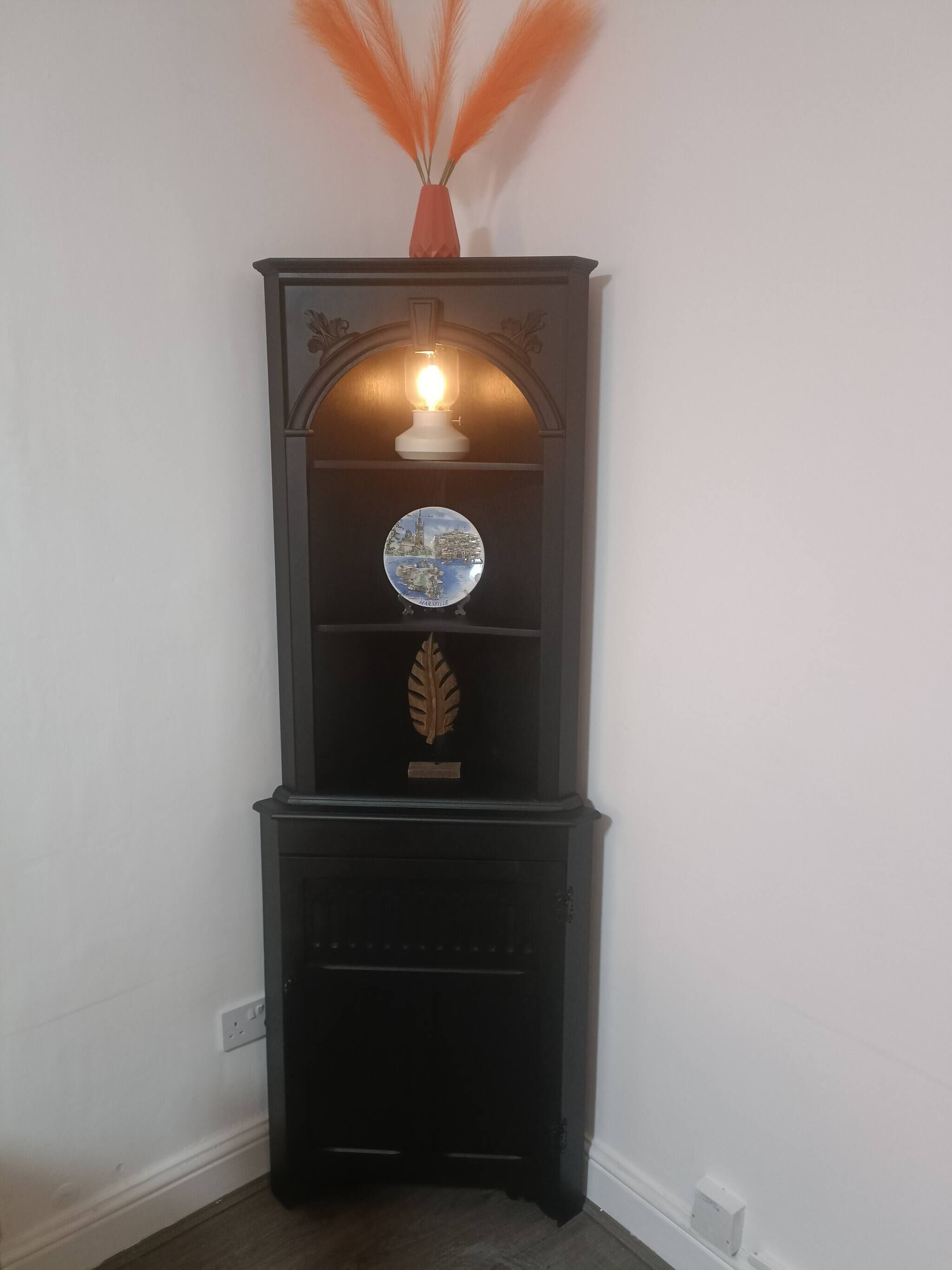 A black cabinet with a decorative plate and a leaf ornament.