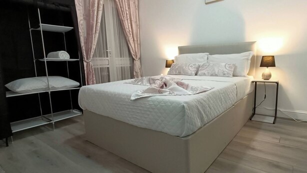 A neatly made bed with a white duvet, two bedside lamps, and a bedside table with a lamp. - Modern & Stylish Retreat  15 Mins to Central London (Barking)