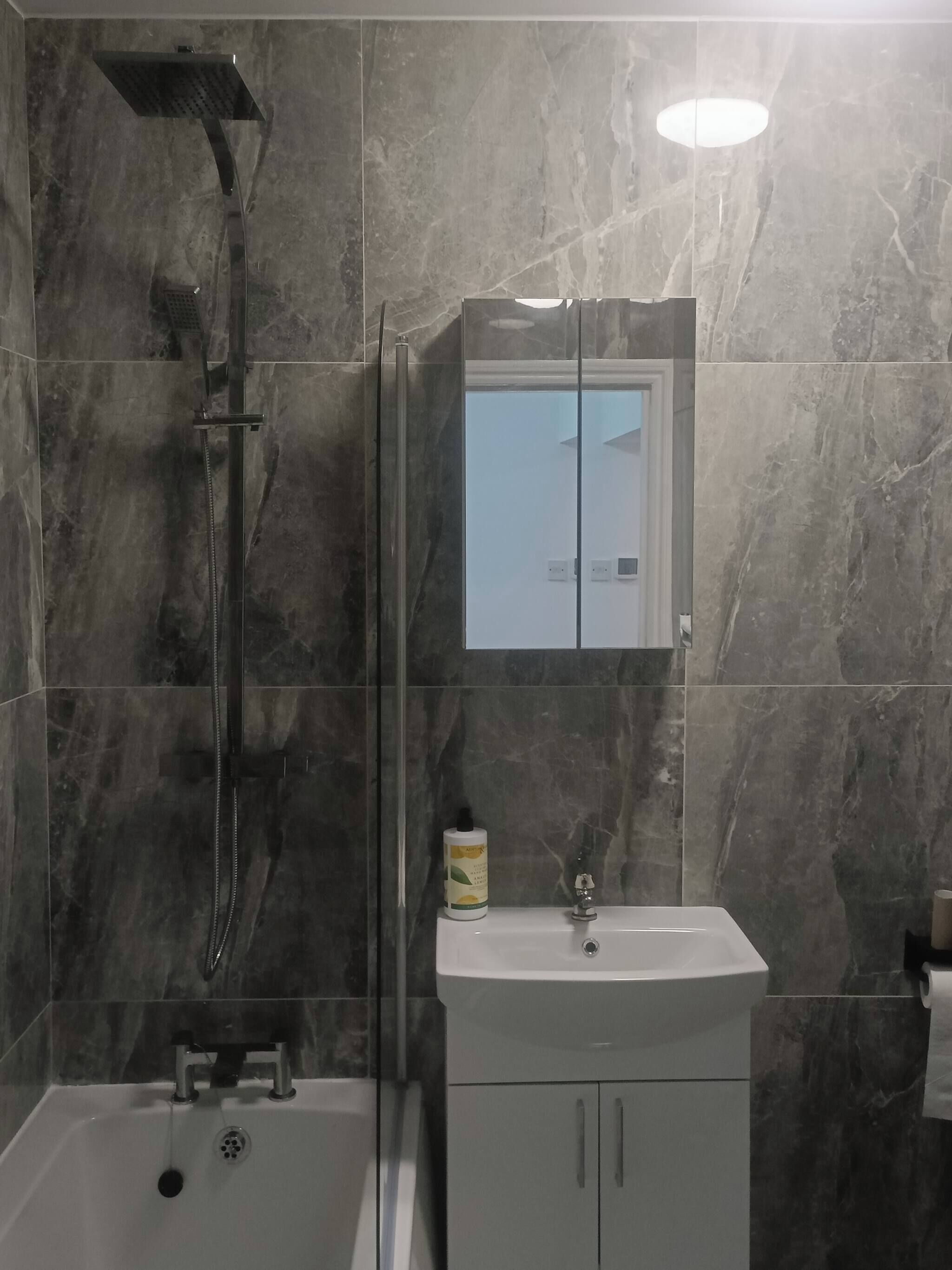 A bathroom with a shower, a sink, and a mirror.