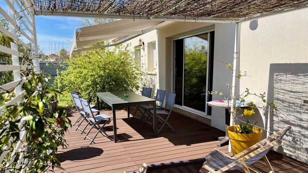 Eine Terrasse im Freien mit Tisch und Stühlen, einem gelben Blumentopf und einem Holzboden.