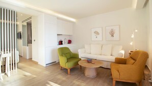 Un soggiorno moderno con un divano bianco, una poltrona verde e una poltrona color senape, e un tavolino rotondo.