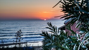 Tramonto sull'oceano con vista sulla spiaggia e un edificio in primo piano.