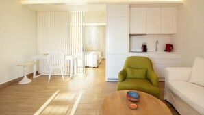 Un soggiorno moderno con pavimento in legno, mobili bianchi, una poltrona verde e un divano bianco.