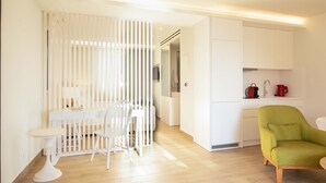 Una stanza moderna e luminosa con zona pranzo, una poltrona verde e mobili bianchi.