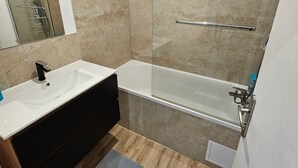 Une salle de bain moderne avec un lavabo blanc, un meuble-lavabo noir et une cabine de douche en verre.