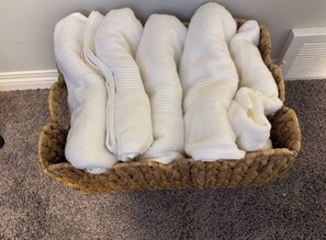 A woven basket filled with white towels placed on a carpeted floor. - Quiet & Comfortable 1-Bedroom (Calgary)