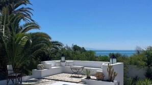 Ein Poolbereich auf dem Dach mit freiem Blick auf den Ozean, umgeben von Palmen und moderner Gartenmöbeln.