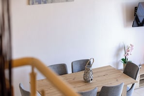 Ein Esstisch mit Stühlen, einem gewebten Korb und einer Topf-Orchidee.