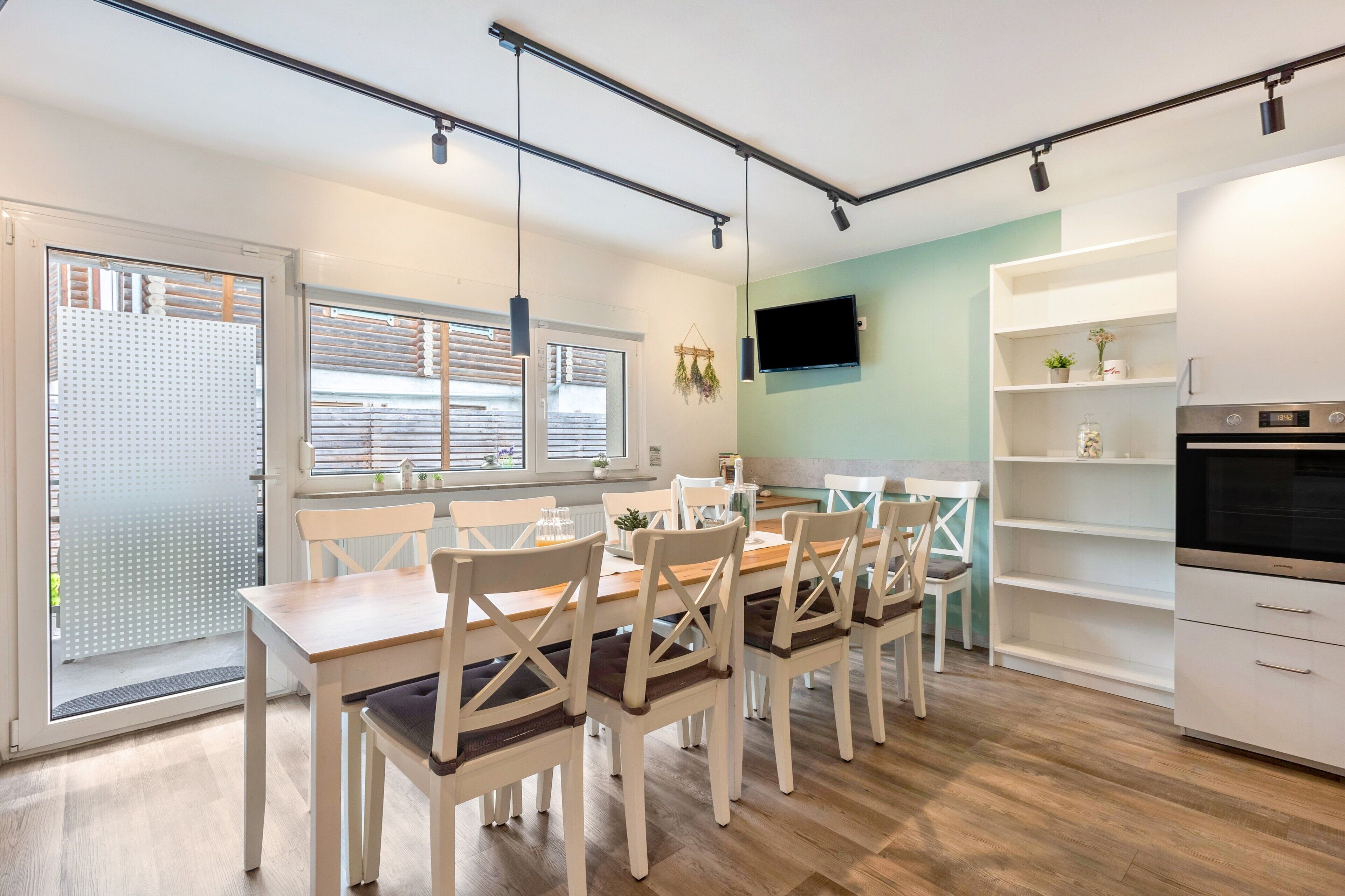 Une cuisine moderne avec un coin repas, un plancher en bois et un téléviseur fixé au mur.