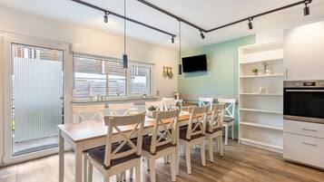 Une cuisine moderne avec un coin repas, un plancher en bois et un téléviseur fixé au mur.