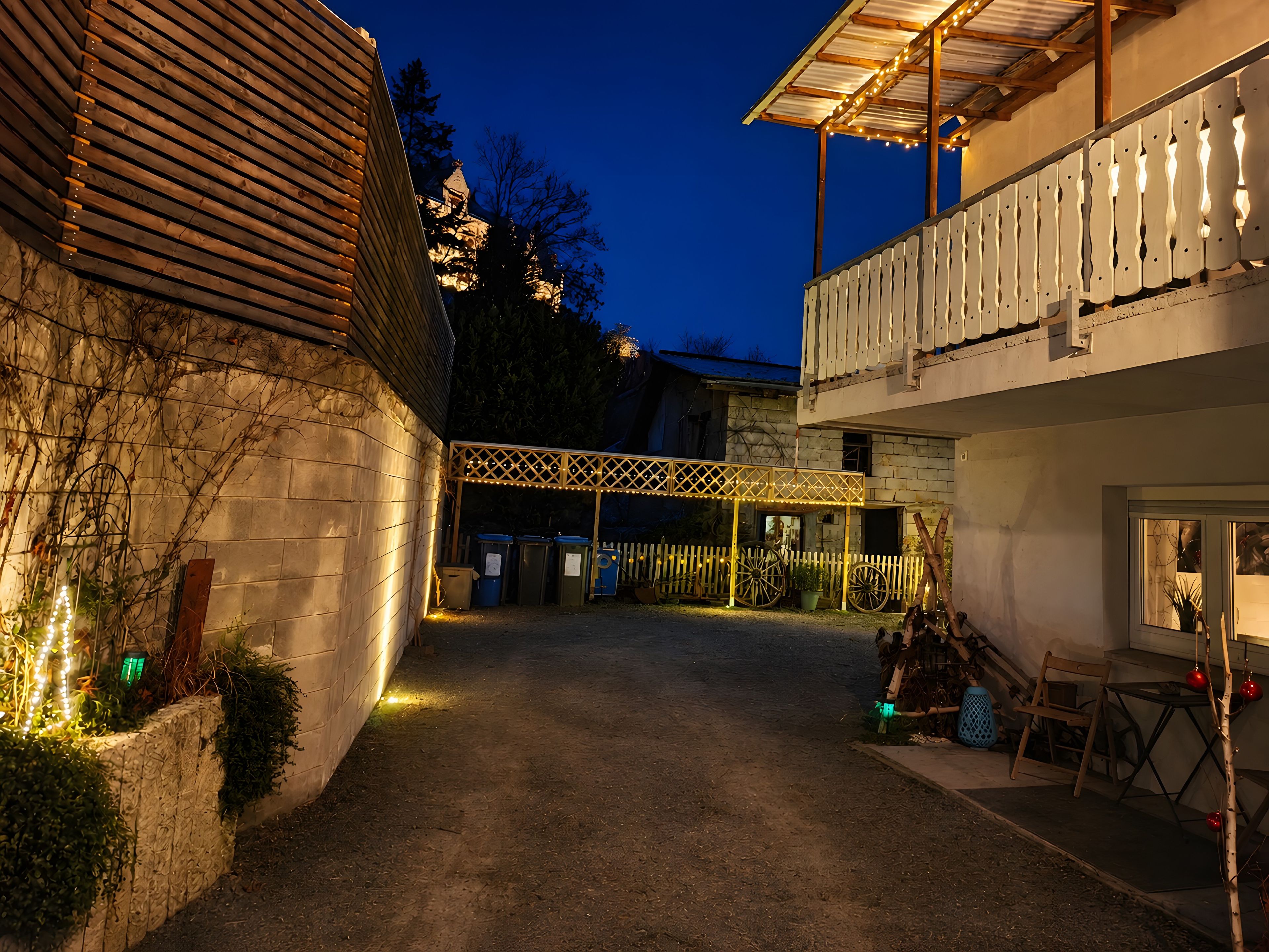 Ein Innenhof mit überdachter Sitzgelegenheit, einem Holzzaun und einem Gebäude mit Balkon.