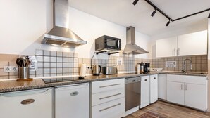 A modern kitchen with white cabinetry, stainless steel appliances, and a tiled backsplash.
