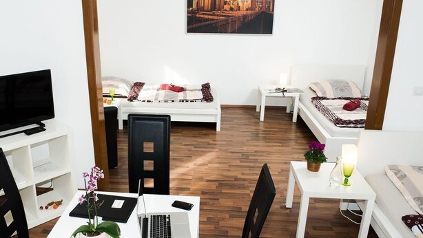 Une chambre d’hôtel moderne équipée d’un lit, d’un bureau, d’une chaise, d’une télévision et ornée d’un tableau représentant un paysage urbain.