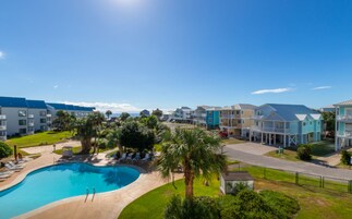 Un resort con piscina, edificios de varios pisos y cielo despejado.
