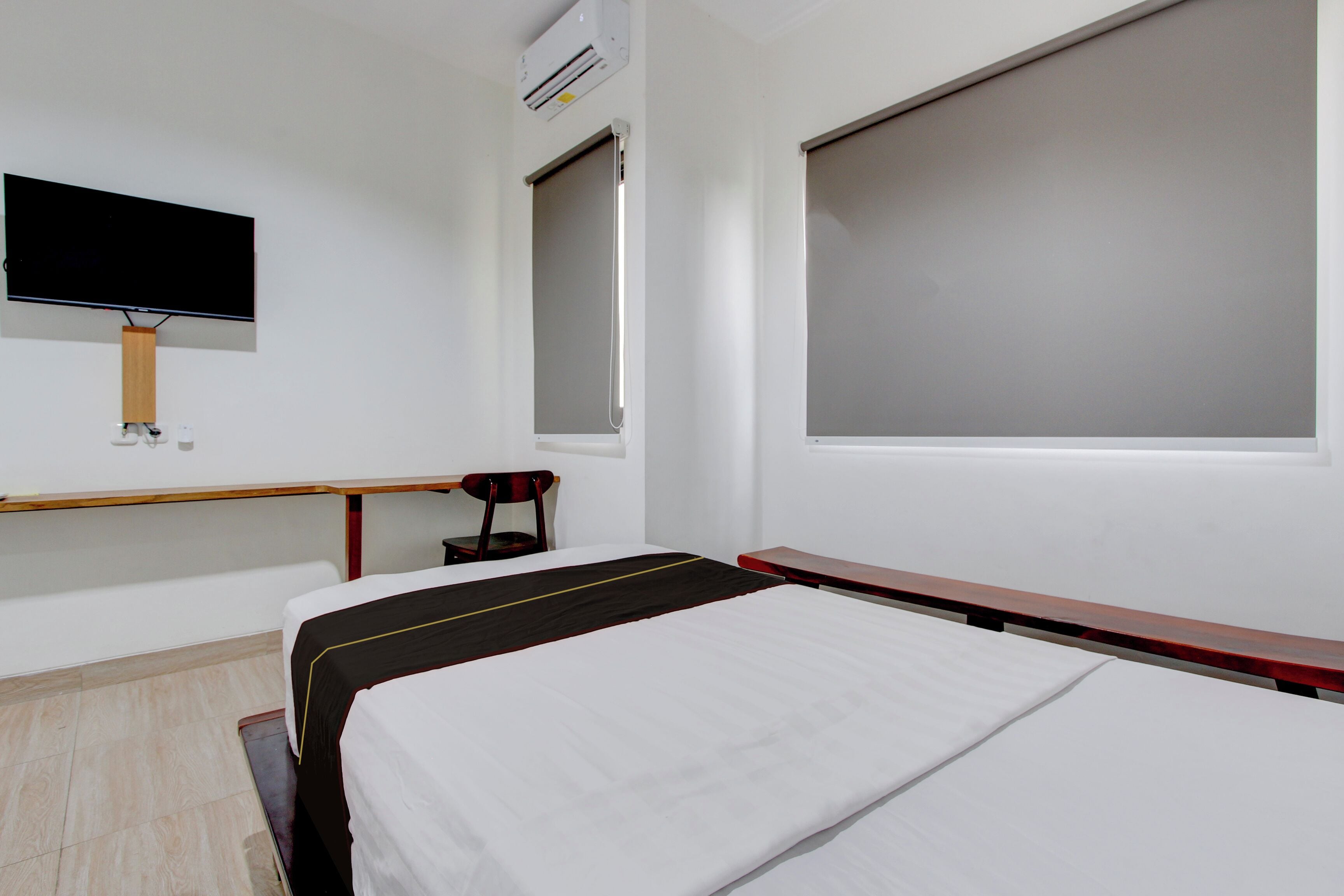 A hotel room with a bed, a desk, a chair, a TV, and a window.