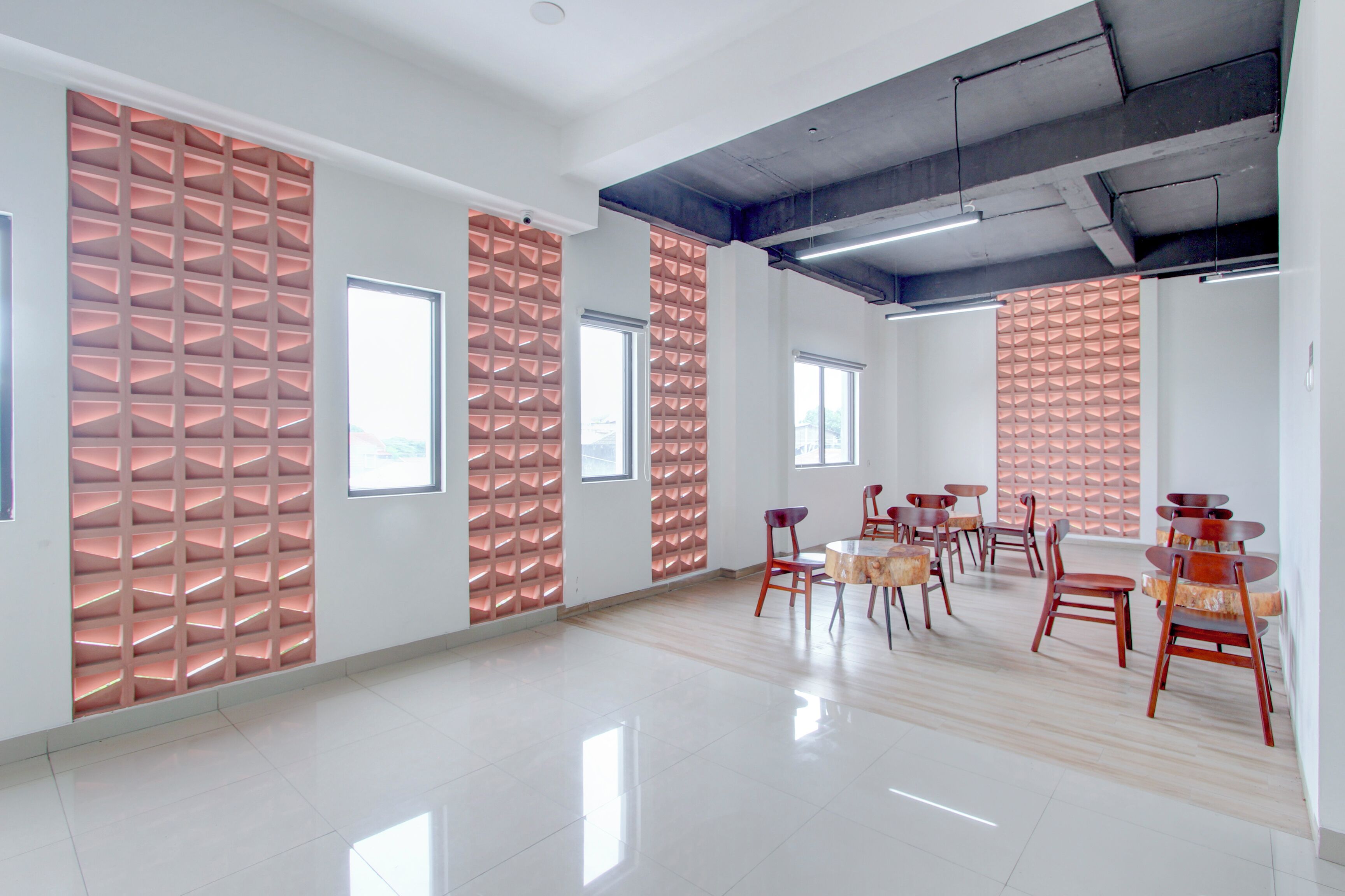 Una habitación amplia y moderna con techos altos, ventanas grandes y un diseño de pared con motivos.