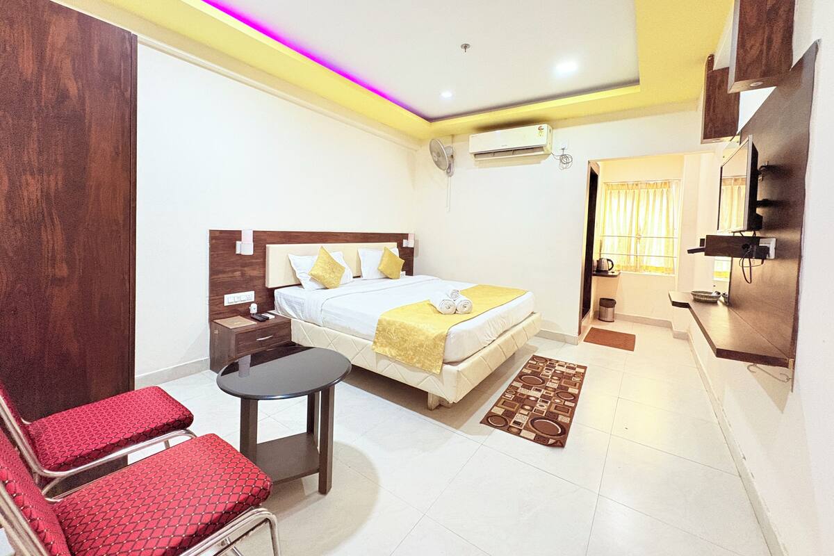 A hotel room with a bed, a desk, a chair, and a TV.